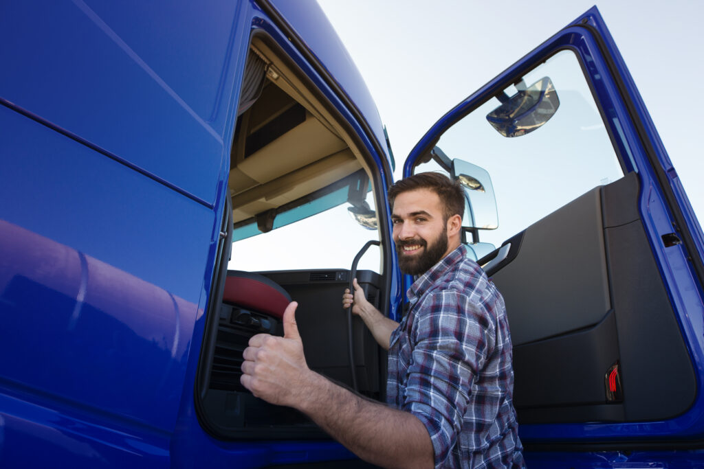 Professional truck driver entering his truck long vehicle and holding thumbs up after getting his tax preparation and filling services done.